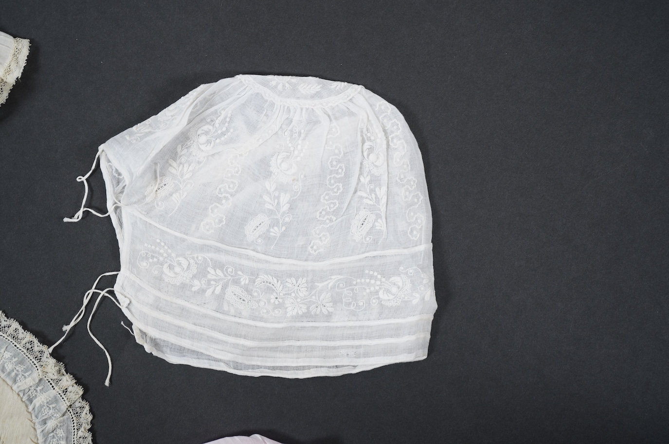 An 18th century Holly Point needle lace panelled linen baby bonnet, an early 19th century white worked baby bib and bonnet and a later 19th century finely ruffed lace bonnet (4). Condition - Holly Point bonnet and bib ha